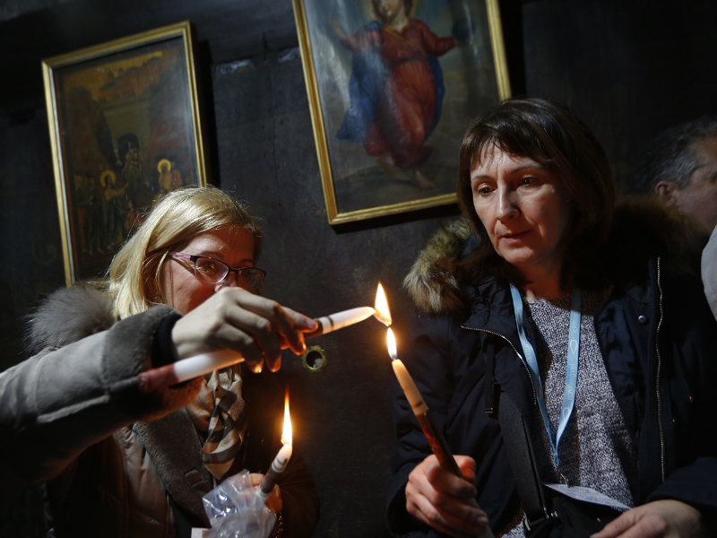 Christian worshipers light candles at the Church of the Nativity, built atop the site where Christians believe Jesus Christ was born, on Christmas Eve, in the West Bank City of Bethlehem, Sunday, Dec. 24, 2017. (AP Photo/Majdi Mohammed)