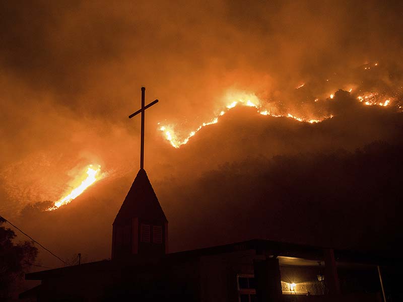Flames from a wildfire advance down a hillside near the Springs of Life Church in Casitas Springs, Calif., on Tuesday, Dec. 5, 2017.  Wind-driven fires tore through California communities Tuesday for the second time in two months, leaving hundreds of homes feared lost and uprooting tens of thousands of people. (AP Photo/Noah Berger)