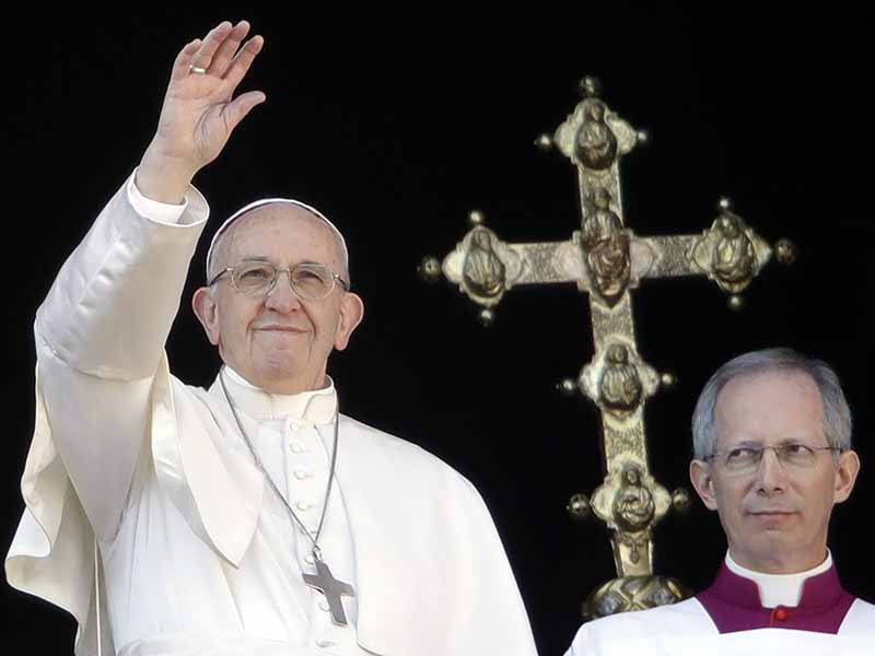 Pope Francis, flanked by Master of Ceremonies Bishop Guido Marini, waves to faithful during the Urbi et Orbi (Latin for ' to the city and to the world' ) Christmas' day blessing from the main balcony of St. Peter's Basilica at the Vatican, Monday, Dec. 25, 2017. (AP Photo/Alessandra Tarantino)