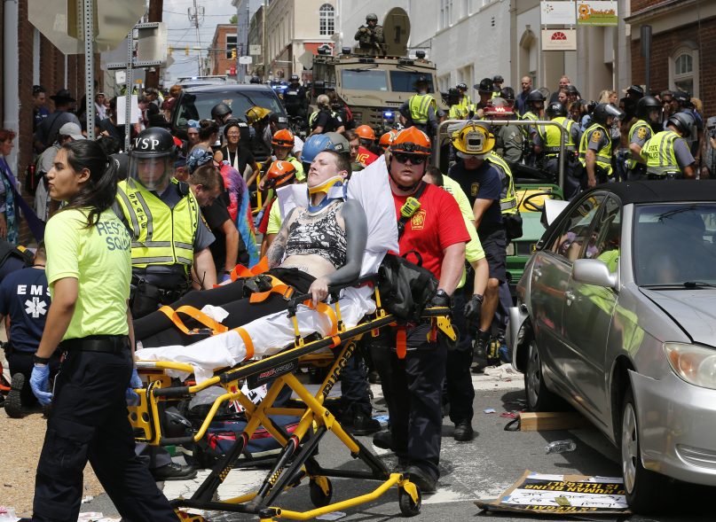 Rescue personnel help injured people after a car ran into a large group of protesters after a white nationalist rally in Charlottesville, Va., on Aug. 12, 2017. One person was killed and 19 were injured in the incident. (AP Photo/Steve Helber)