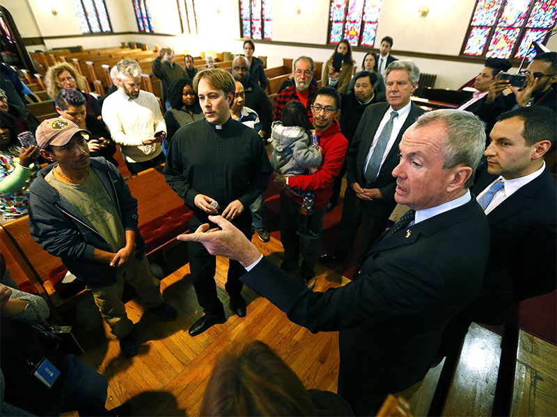 New Jersey Governor Phil Murphy, right, speaks with parishioners at Highland Park Reformed Church on Jan. 25, 2018, in Highland Park, NJ. Harry Pangemanan, left, an Indonesian man, claimed sanctuary at the church after ICE agents went to his front door. (Photo by Bob Karp via USAToday)