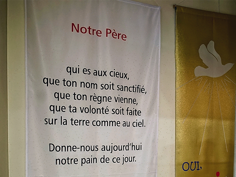 A banner with the new French translation of the Lord's Prayer, at left, for churches that want to help parishioners recite it aloud during Mass, on sale in a religious goods shop in Paris, France, on Jan. 30, 2018. RNS photo by Tom Heneghan