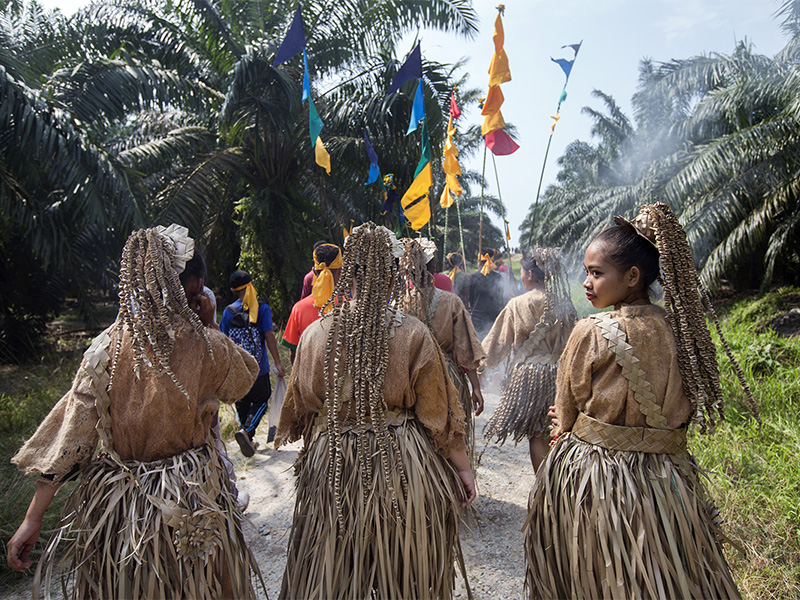 A piece of burning sandalwood fills the air with incense as the Mah Meri procession walks towards the beach on Feb. 20, 2018.  Women wear traditional outfits made from palm fronds and tree bark.  RNS photo by Alexandra Radu