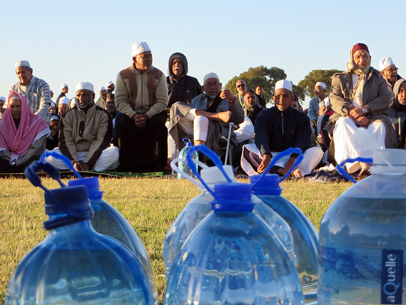The Muslim Judicial Council South Africa joined Habibia Soofie Masjid and Masjidul-Quds to lead more than 1,000 Muslims in an early morning prayer for rain at the Rylands sports complex in Athlone, Cape Town, on Feb. 4, 2018. Worshippers donated bottled water, foreground, and many mosques throughout Cape Town have installed aerators on taps or are providing worshippers with spray bottles or single cups of water to perform ablutions.  RNS photo by Brian Pellot