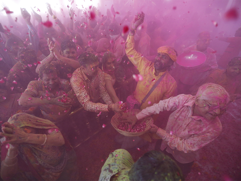 An Indian man, wearing yellow, throws flowers on devotees as others throw colored powder during a Holi festival celebration at Lord Jagannath Hindu temple in Ahmadabad, India, on March 2, 2018. The Hindu festival, a celebration of warm weather, good harvests and the defeat of evil, brings out millions of people, from toddlers to the elderly, to throw powder at one another and play with water balloons and squirt guns. (AP Photo/Ajit Solanki)