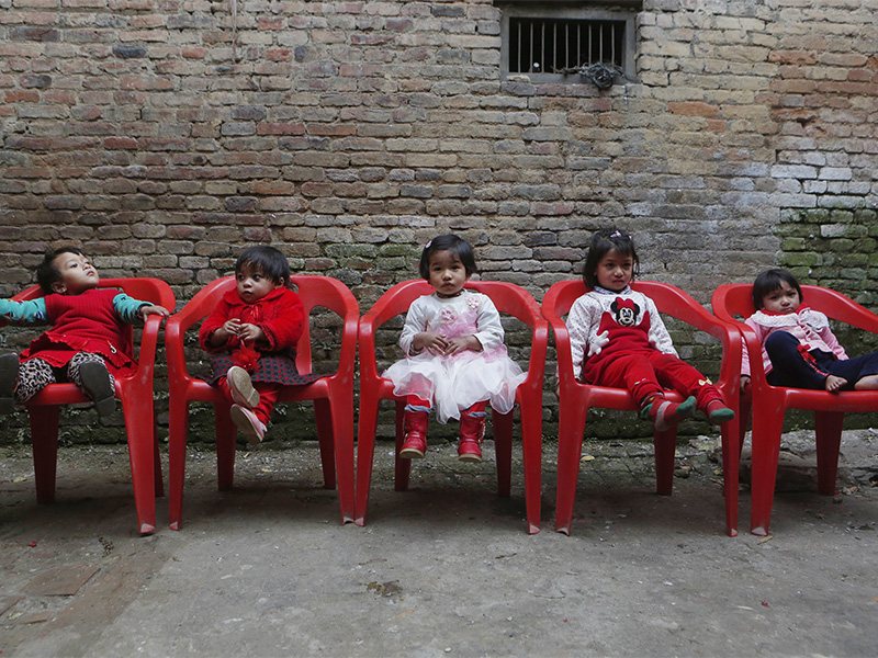 Young Nepalese girls sit in chairs as they wait during the selection of a new living goddess, locally known as 