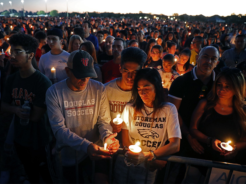 Jorge Zapata, Jr., center, a student at Marjory Stoneman Douglas High School, holds candles with his mother Lavinia Zapata, and father Jorge Zapata, Sr., during a candlelight vigil for the victims of the Wednesday shooting at the school, in Parkland, Fla., Thursday, Feb. 15, 2018. (AP Photo/Gerald Herbert)