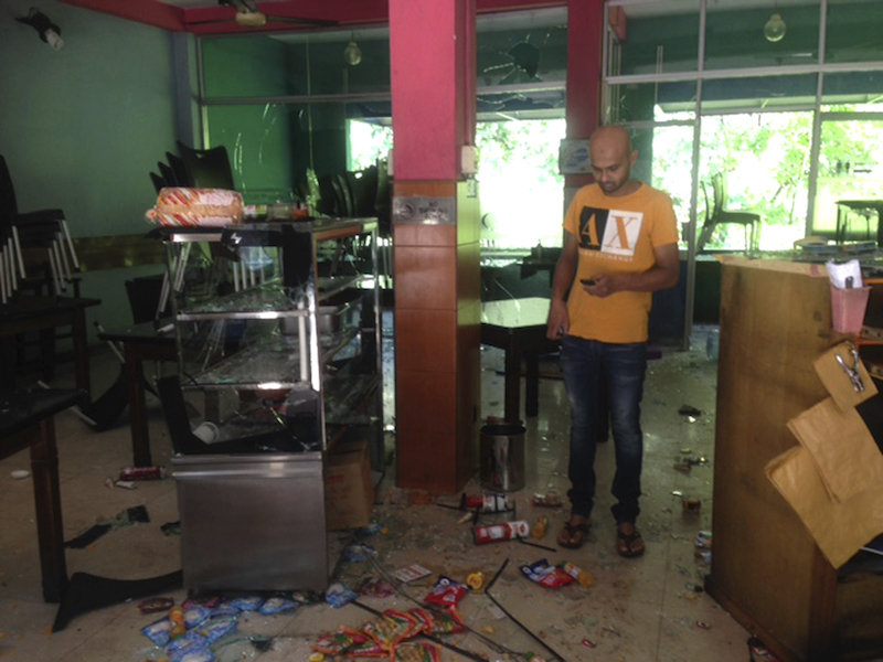 Mohamed Ramzeen makes a call from his mobile standing in his vandalized small restaurant in Pilimathalawa, Sri Lanka, Thursday, March 8, 2018. About 50 people broke into Mohamed Ramzeen's small restaurant  on Wednesday night while the curfew was in effect, destroying nearly everything they found, he said. Buddhist mobs swept through Muslim neighborhoods in Sri Lanka's central hills, destroying stores and restaurants despite a curfew, a state of emergency and a heavy deployment of security forces. (AP Photo/ Bharatha Mallawarachchi)