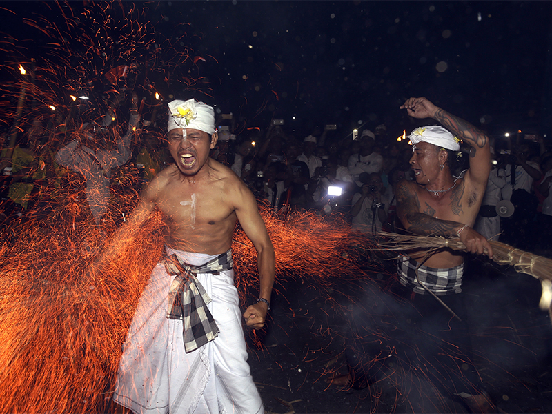 A Balinese man is hit with flaming coconut leaves during the fire fight ritual called 'Lukat Gni' before Nyepi, the annual day of silence marking the Balinese Hindu new year in Klungkung, Bali, Indonesia, on March 16, 2018. Bali's annual Day of Silence is so sacred that even reaching for a smartphone to send a tweet or upload a selfie to social media could cause offense. This year it will be nearly impossible to do that anyway, all phone companies have agreed to shut down the mobile internet for 24 hours during the holiday that marks the New Year on the predominantly Hindu island. (AP Photo/Firdia Lisnawati)