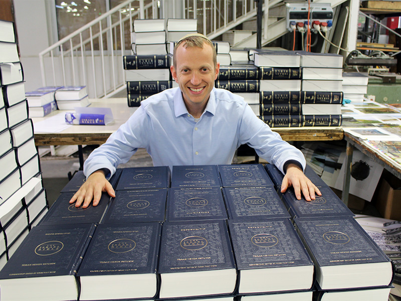 Rabbi Tuly Weisz with stacks of The Israel Bible, which he edited. Photo courtesy of Israel365