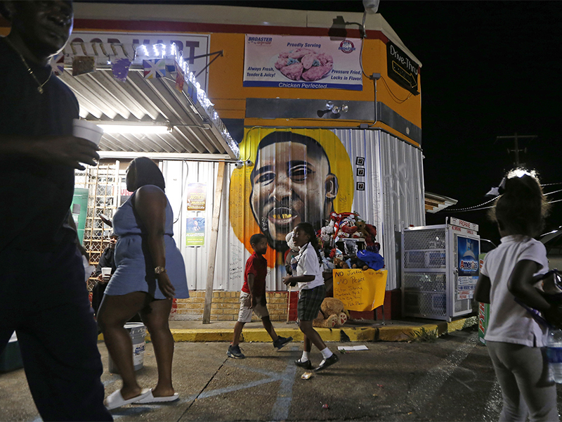 People congregate on May 2, 2017, in front of a mural of Alton Sterling outside the Triple S Food Mart in Baton Rouge, La., where Sterling was killed in 2016. The investigation of the deadly police shooting that inflamed racial tensions in Louisiana’s capital ended without criminal charges against two white officers who confronted Sterling, a black man, outside the convenience store two summers ago. Experts in police tactics think the bloodshed could have been avoided if the Baton Rouge officers had done more to defuse the encounter with Sterling. They say poor police tactics and techniques may have aggravated the volatile confrontation, which lasted less than 90 seconds. (AP Photo/Gerald Herbert)