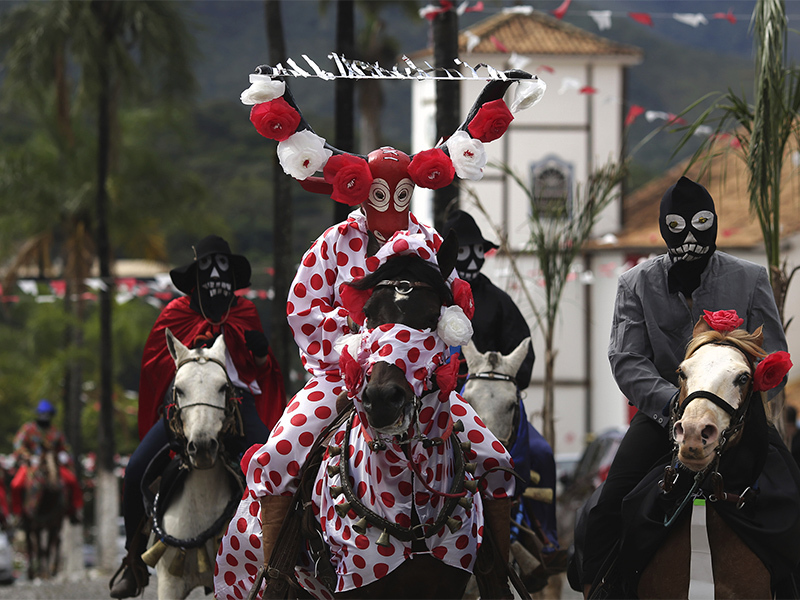 A horseman wearing an elaborate bull mask rides past Our Lady of the Rosary church during the 