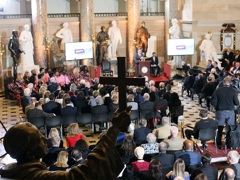 A statue of Friar Junípero Serra, one of two statues that represent the state of California in Statuary Hall, is seen in the foreground as a National Day of Prayer event is held in the Capitol on May 3, 2018. RNS photo by Adelle M. Banks