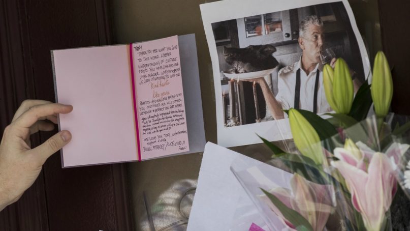 A mourner reads a sympathy card left for Anthony Bourdain at a make shift memorial outside the building that once housed Le Halles restaurant on Park Avenue, Friday, June 8, 2018, in New York. Bourdain, the celebrity chef and citizen of the world who inspired millions to share his delight in food and the bonds it created, was found dead Friday in his hotel room in France while working on his CNN series on culinary traditions. He was 61. (AP Photo/Mary Altaffer)