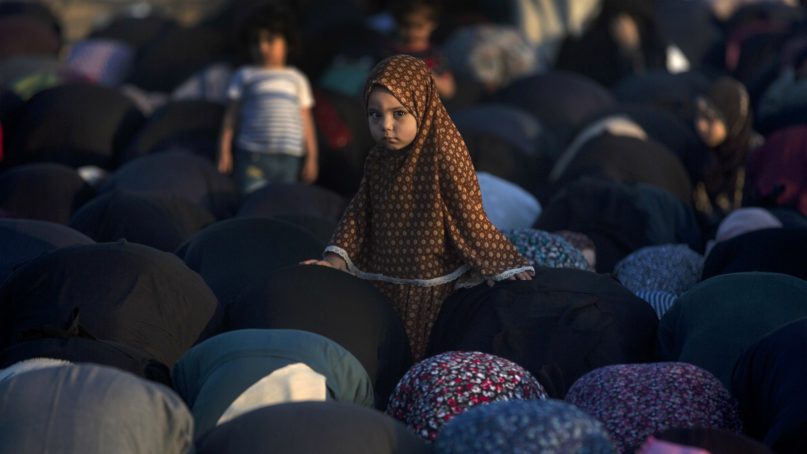 A Palestinian girl stands in the middle of Muslim women performing Eid al-Fitr prayers marking the end of the holy fasting month of Ramadan, in Eastern Gaza City, Friday, June 15, 2018. (AP Photo/Khalil Hamra)