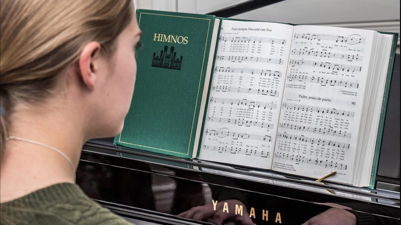 A young woman plays a hymn on the piano from the Mormon church's Spanish hymnbook. Photo courtesy of Intellectual Reserve Inc.