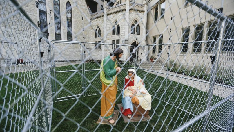 This Tuesday, July 3, 2018 photo shows statues of Mary, Joseph and the baby Jesus in a cage of fencing topped with barbed wired on the lawn of Monument Circle's Christ Church Cathedral in Indianapolis. The statues were erected to protest the Trump administration's zero tolerance immigration policy. (Ebony Cox/The Indianapolis Star via AP)