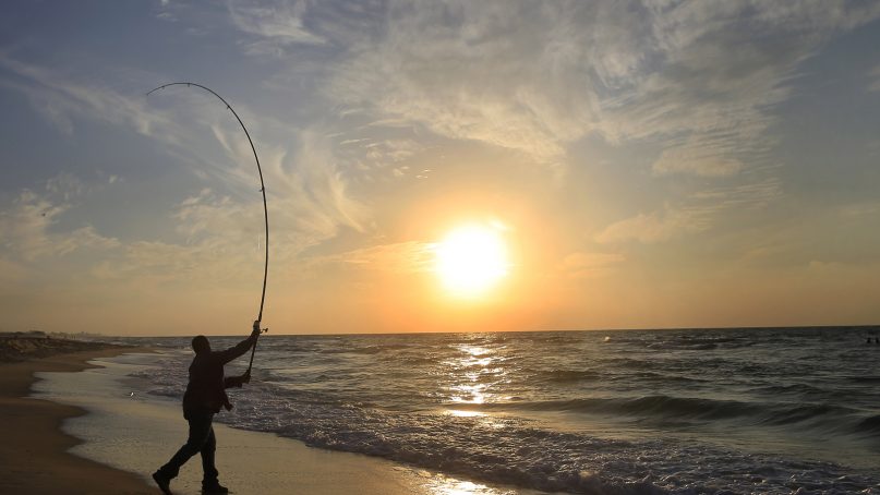 A man fishes at a sunset on a beach south of Ashkelon, near the Israel's border with Gaza Strip, Saturday, Dec. 7, 2013. (AP Photo/Tsafrir Abayov)