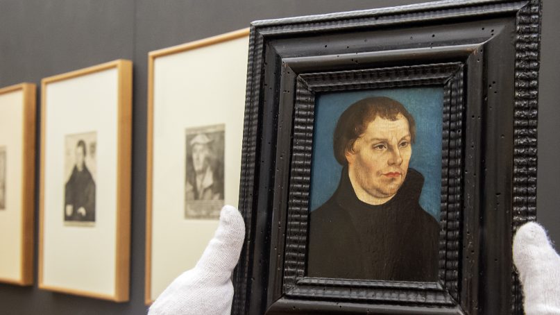 A museum employee presents an original Lucas Cranach the Elder painting of Martin Luther (1525/1526) in front of counterfeits during the press preview of the exhibition 