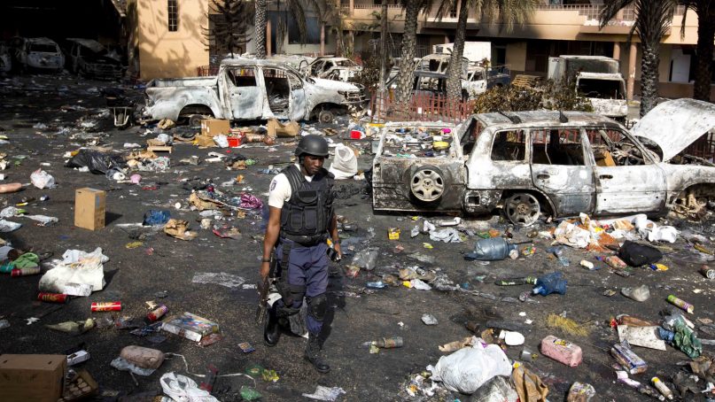 A police officer walks through the parking lot of the Delimart supermarket complex, where vehicles sit charred and looted merchandise lies scattered after two days of protests against a planned hike in fuel prices in Port-au-Prince, Haiti, Sunday, July 8, 2018. Government officials had agreed to reduce subsidies for fuel as part of an assistance package with the International Monetary Fund, but the government suspended the fuel hike after widespread violence broke out. (AP Photo/Dieu Nalio Chery)