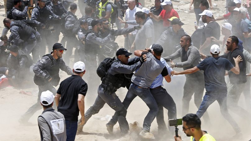Palestinians protesting the planned demolition of the West Bank hamlet of Khan al-Ahmar fight with Israeli police officers, Wednesday, July 4, 2018. Israel says the structures were illegally built and pose a threat to residents because of their proximity to a highway. Critics say it is nearly impossible to get building permits, and that the residents are being removed to clear the way for Jewish settlements. (AP Photo/Majdi Mohammed)