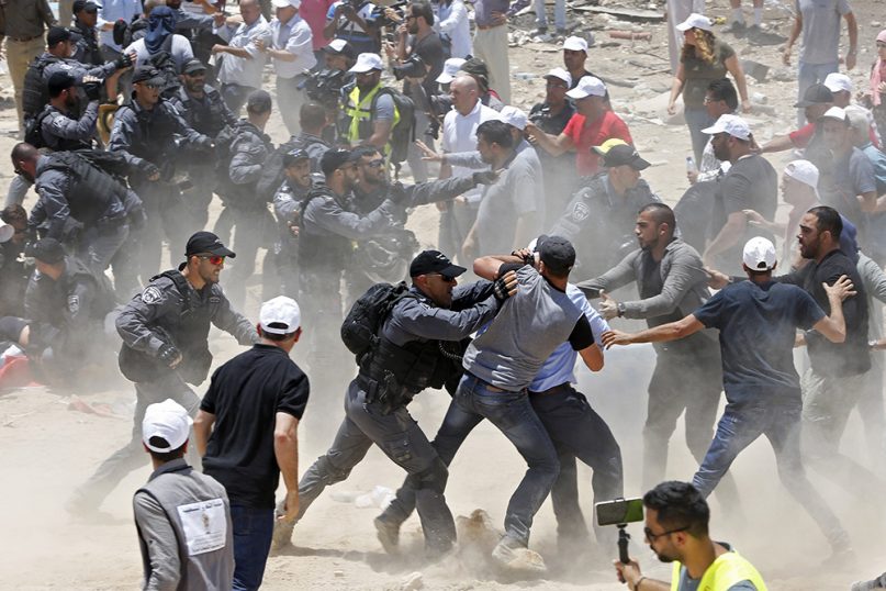 Palestinians protesting the planned demolition of the West Bank hamlet of Khan al-Ahmar fight with Israeli police officers, Wednesday, July 4, 2018. Israel says the structures were illegally built and pose a threat to residents because of their proximity to a highway. Critics say it is nearly impossible to get building permits, and that the residents are being removed to clear the way for Jewish settlements. (AP Photo/Majdi Mohammed)