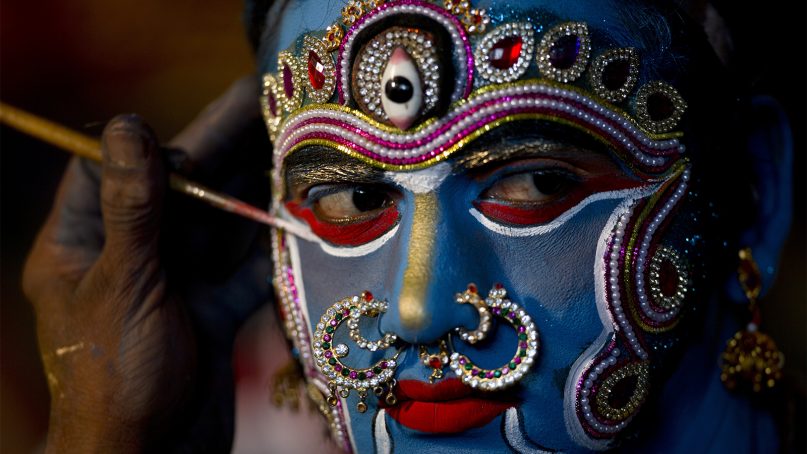An Indian artist gets make up before a performance during a procession of the “Bonalu