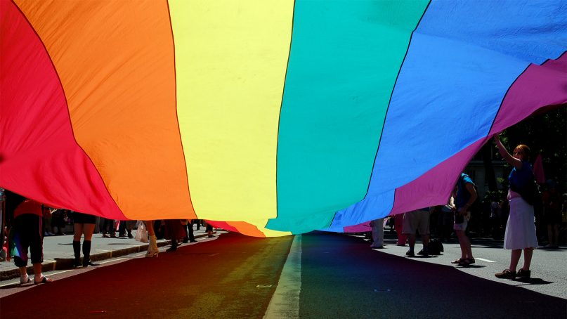 People parade with a pride flag. Photo courtesy of Creative Commons