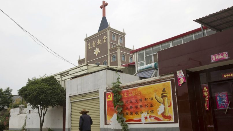 In this photo taken June 2, 2018, a resident walks past a government billboard citing core values of the Communist Party near a church in the city of Pingdingshan in central China's Henan province.  Under President Xi Jinping, China’s most powerful leader since Mao Zedong, believers are seeing their freedoms shrink dramatically even as the country undergoes a religious revival. Experts and activists say that as he consolidates his power, Xi is waging the most severe systematic suppression of Christianity in the country since religious freedom was written into the Chinese constitution in 1982. (AP Photo/Ng Han Guan)