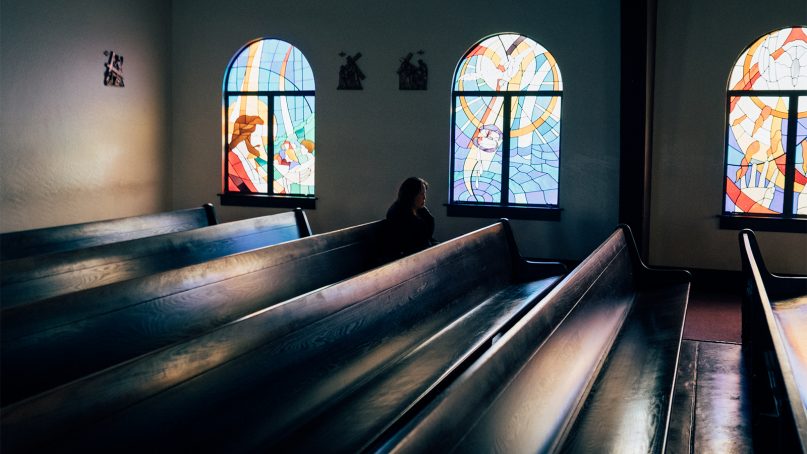 A woman sits alone in church pews.  Photo by Anthony Nguyen/Creative Commons