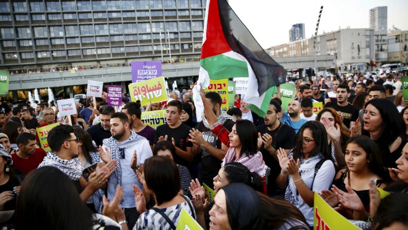 Israeli Arabs hold a Palestinian flag during a protest against the Jewish nation bill in Tel Aviv, Israel, on Aug. 11, 2018. The recently passed law enshrines Israel's Jewish character and downgrades the standing of Arabic from an official to a 