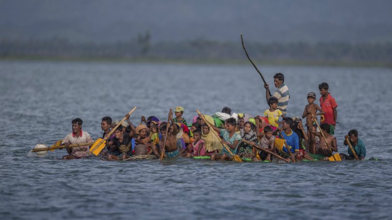 In this Nov. 12, 2017, file photo, Rohingya Muslims aboard a makeshift raft made with plastic containers cross over the Naf river from Myanmar into Bangladesh, near Shah Porir Dwip, Bangladesh. Myanmar on Thursday, Aug. 9, 2018, sharply rejected an attempt by the International Criminal Court to consider the country's culpability for activities that caused about 700,000 minority Rohingya Muslims to flee to Bangladesh for safety. The office of State Counsellor Aung San Suu Kyi, the country's leader, said in a statement posted online that the court in the Netherlands has no jurisdiction over Myanmar because it is not a member state. (AP Photo/A.M. Ahad, File)