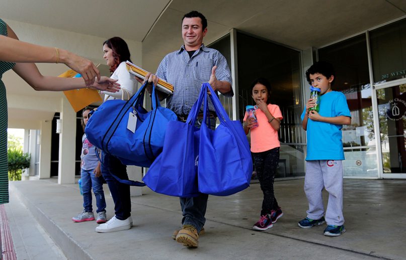 FILE - Immigrants from Honduras, Gerarado Reconco Lara, center, with his children Maria, 6, and Gerardo, 8, leave a Catholic Charities facility July 23, 2018, in San Antonio. The family was reunited the night before. (AP Photo/Eric Gay)
