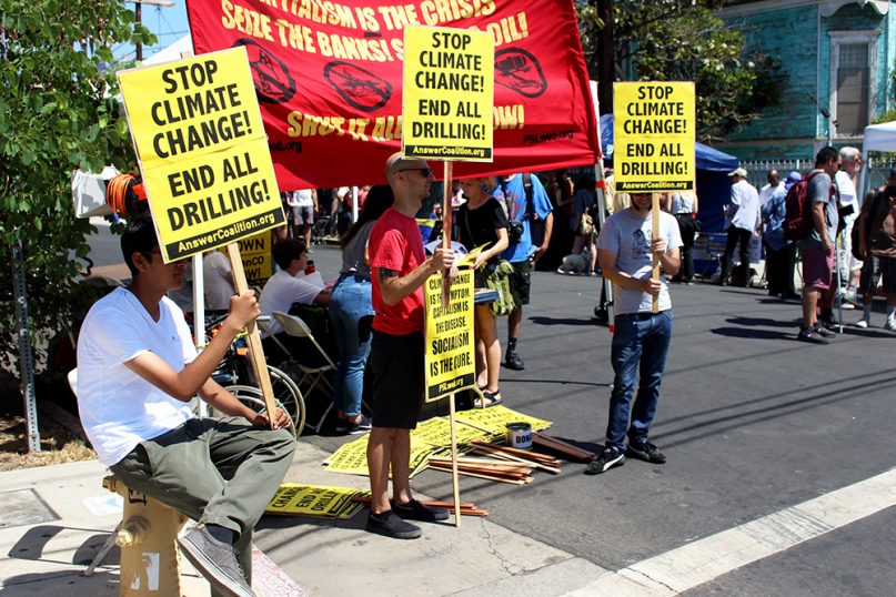 Attendees line the streets with signs during the Rise L.A. For Climate, Jobs and Justice Rally in the University Park neighborhood of Los Angeles on Sept. 8, 2018. RNS photo by Heather Adams