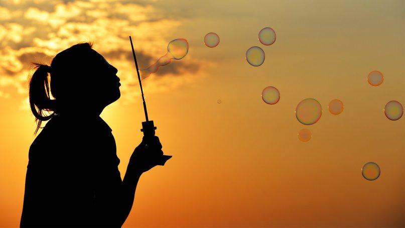 A girl blows bubbles at dusk.  Photo courtesy of Pixabay/Creative Commons