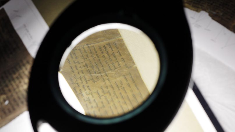 Conservators examine a portion of the Dead Sea Scrolls containing the Ten Commandments before the scrolls' installation at Discovery Times Square in New York, Thursday, Dec. 15, 2011. (AP Photo/Seth Wenig)
