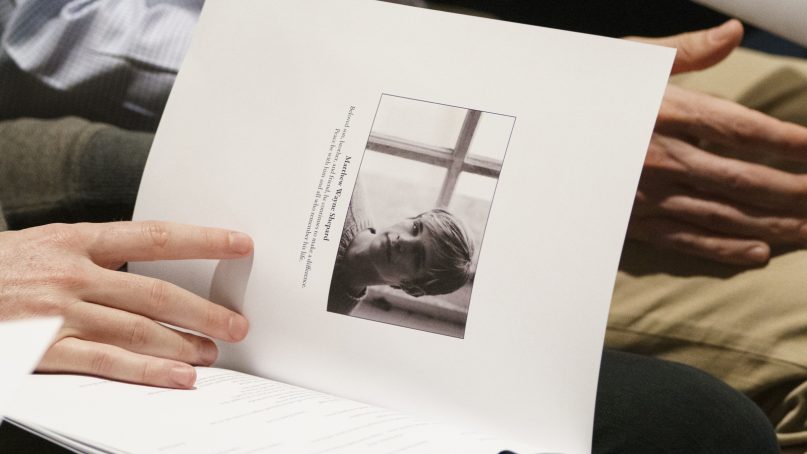 Mourners hold programs with the image of Matthew Shepard during a 