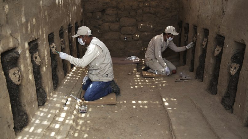 Archaeologists clean the clay masks of wooden idols that protect the entrance to a ceremonial center in the pre-Columbian adobe city of Chan Chan, near Trujillo, Peru, on Oct. 22, 2018. Peru's Ministry of Culture presented the wooden idols as part of a series of important archaeological discoveries in the Chan Chan citadel belonging to the ancient Chimu empire who were conquered by the Incas in the late 15th century. (AP Photo/Martin Mejia)