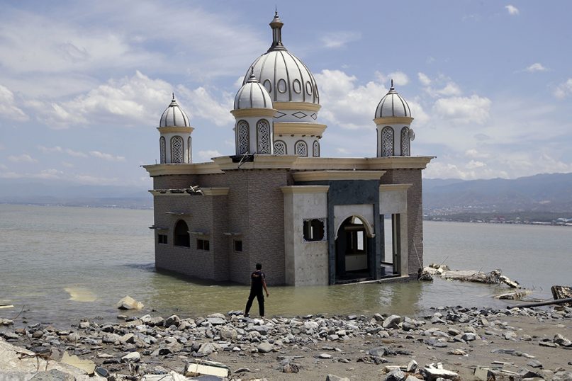A man looks at a damaged mosque that is isolated by water after its bridge was broken due to the massive earthquake and tsunami in Palu, Central Sulawesi, Indonesia, on Oct. 5, 2018. (AP Photo/Aaron Favila)