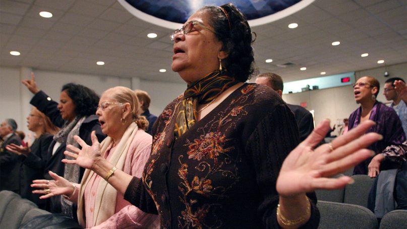 Maria Antonetty, foreground, joins others in a Spanish Easter service at the Primitive Christian Church in New York on April 12, 2009. (AP Photo/Tina Fineberg)