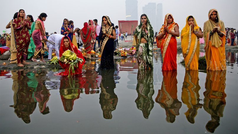 Hindu devotees pray to the Sun god as they stand in knee deep waters of the River Yamuna during Chhath Puja festival in New Delhi, India, on Nov. 13, 2018. During Chhath Puja, an ancient Hindu festival, rituals are performed to thank the Sun god for sustaining life on Earth. (AP Photo/Altaf Qadri)