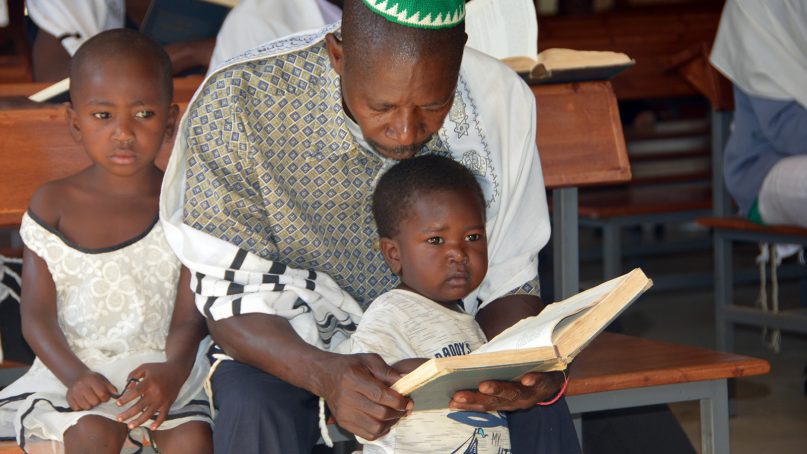 A man attends a Pentecostal church service with his children in eastern Uganda on Nov. 18, 2018. There are a number of Christians and churches in Uganda that believe seeking medical attention demonstrates a lack of faith in God. RNS photo by Doreen Ajiambo