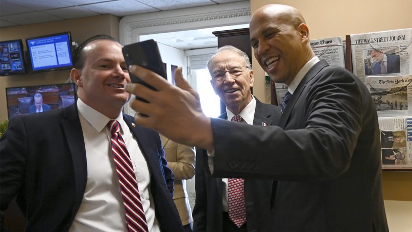 Sen. Cory Booker, D-N.J., right, joins Sen. Chuck Grassley, R-Iowa, center, and Sen. Mike Lee, R-Utah, left, in an Instagram Live post before they participate in a news conference on Capitol Hill in Washington, on Dec. 19, 2018, on prison reform legislation. A criminal justice bill passed in the Senate gives judges more discretion when sentencing some drug offenders and boosts prisoner rehabilitation efforts. (AP Photo/Susan Walsh)
