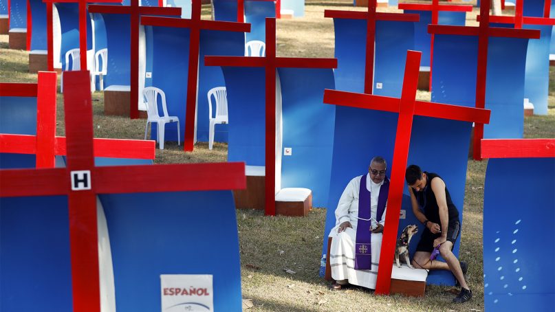 Carlos Felice, a 37-year-old Venezuelan living in Panama for five years, right, confesses to local Catholic priest Gabriel Agustin Guardia in an outdoor confessional, after exercising with his dog at Omar Park in Panama City, Wednesday, Jan. 23, 2019. Pope Francis will arrive later Wednesday for a five-day visit to the Central American country. (AP Photo/Rebecca Blackwell)