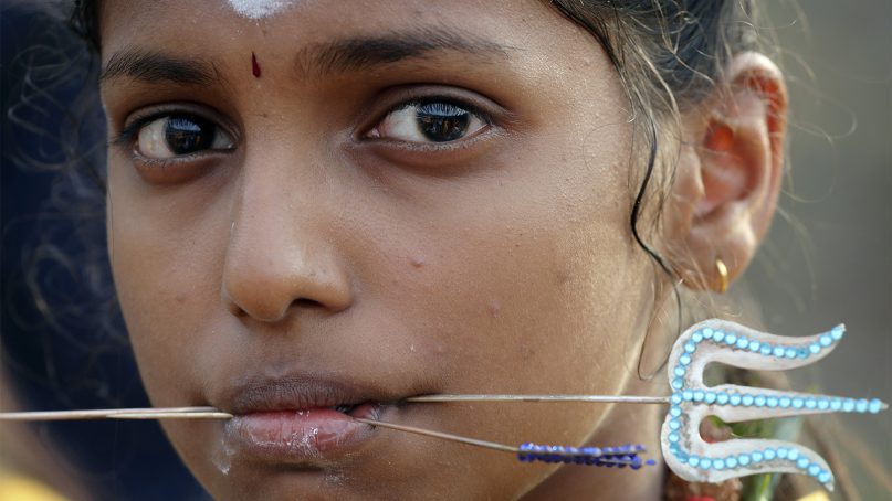 A young female Hindu devotee gets her cheeks pierced with a metal rod as she participates in a religious procession during Thaipusam festival at Batu Caves in Kuala Lumpur, Malaysia on Jan. 21, 2019. Thaipusam, which is celebrated in honor of Hindu god Lord Murugan, is an annual procession by Hindu devotees seeking blessings, fulfilling vows and offering thanks. (AP Photo/Vincent Thian)