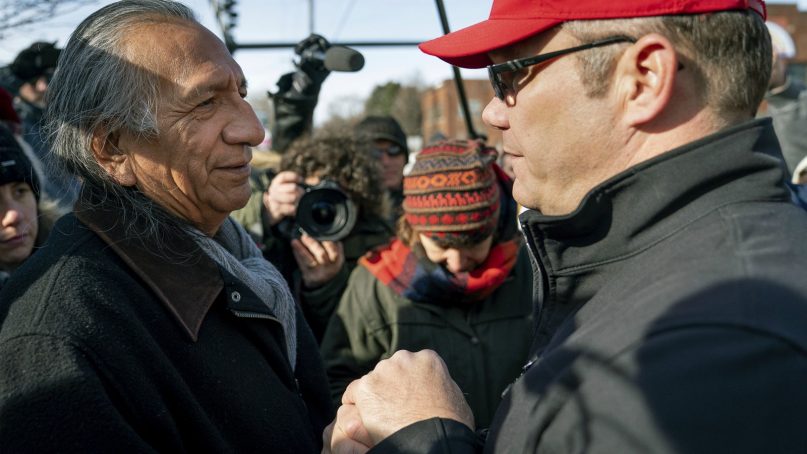 Guy Jones, left, and a supporter of President Donald Trump named Don join hands during a gathering of Native American supporters in front of the Catholic Diocese of Covington in Covington, Ky., Tuesday, Jan. 22, 2019. Jones organized Tuesday's gathering. (AP Photo/Bryan Woolston)