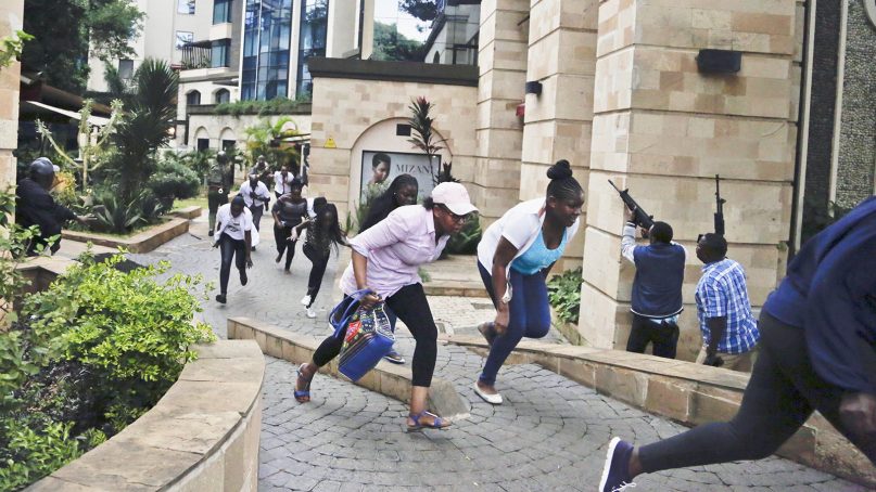Civilians flee as security forces aim their weapons at a hotel complex in Nairobi, Kenya, on Jan. 15, 2019. Extremists launched a deadly attack on a luxury hotel in Kenya's capital, sending people fleeing in panic as explosions and heavy gunfire reverberated through the complex. (AP Photo/Khalil Senosi)