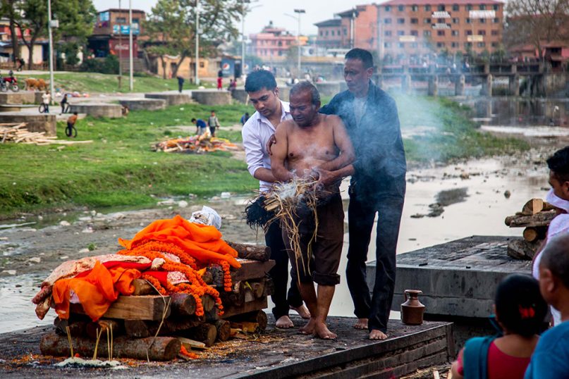 A group of men move to ignite the funeral pyre of a relative at the  Pashupatinath temple in Kathmandu, Nepal. Cremations are held every day at the famous Hindu temple. RNS photo by Jair Cabrera Torres