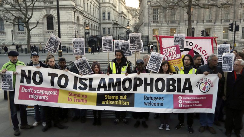 People hold up a banner during a 'Unity Vigil' against racism and Islamophobia, backdropped by the gates of Downing Street in London, on March 24, 2017. (AP Photo/Matt Dunham)
