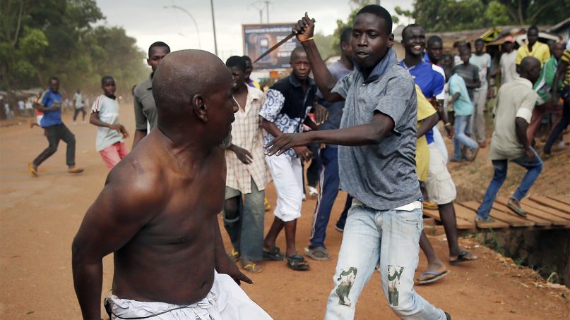 In this Dec. 9, 2013, file photo, a Christian man, right, chases a suspected Muslim Seleka officer in civilian clothes with a knife near the airport in Bangui, Central African Republic. Central African Republic and 14 rebel groups signed a peace deal on Wednesday, Feb. 6, 2019 even as some expressed alarm about the possible suspension of prosecutions after five years of bloody conflict.  (AP Photo/Jerome Delay)